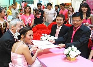 British national Gary Howard, 52, and new bride Kwanruen Laklaem, 32, seated left, tie the knot on Valentine’s Day in front of Banglamung District officials at Central Festival Pattaya Beach.
